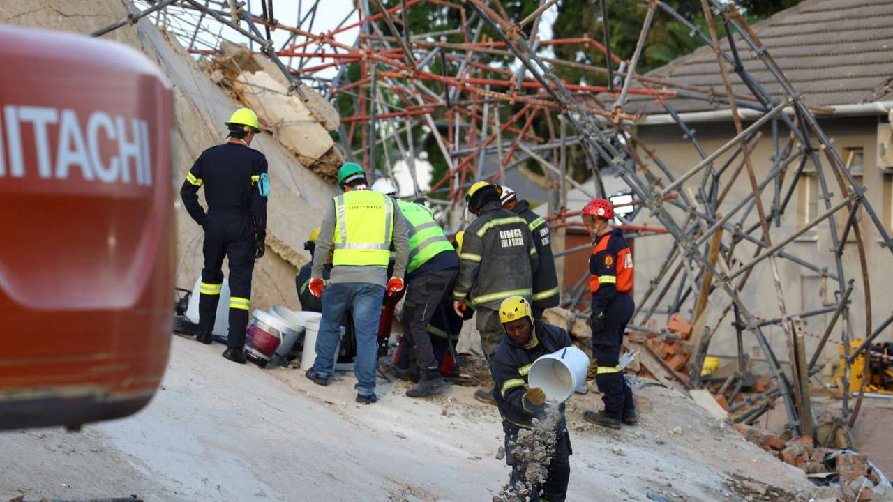 Rescuers work to rescue construction workers trapped under a building that collapsed in George