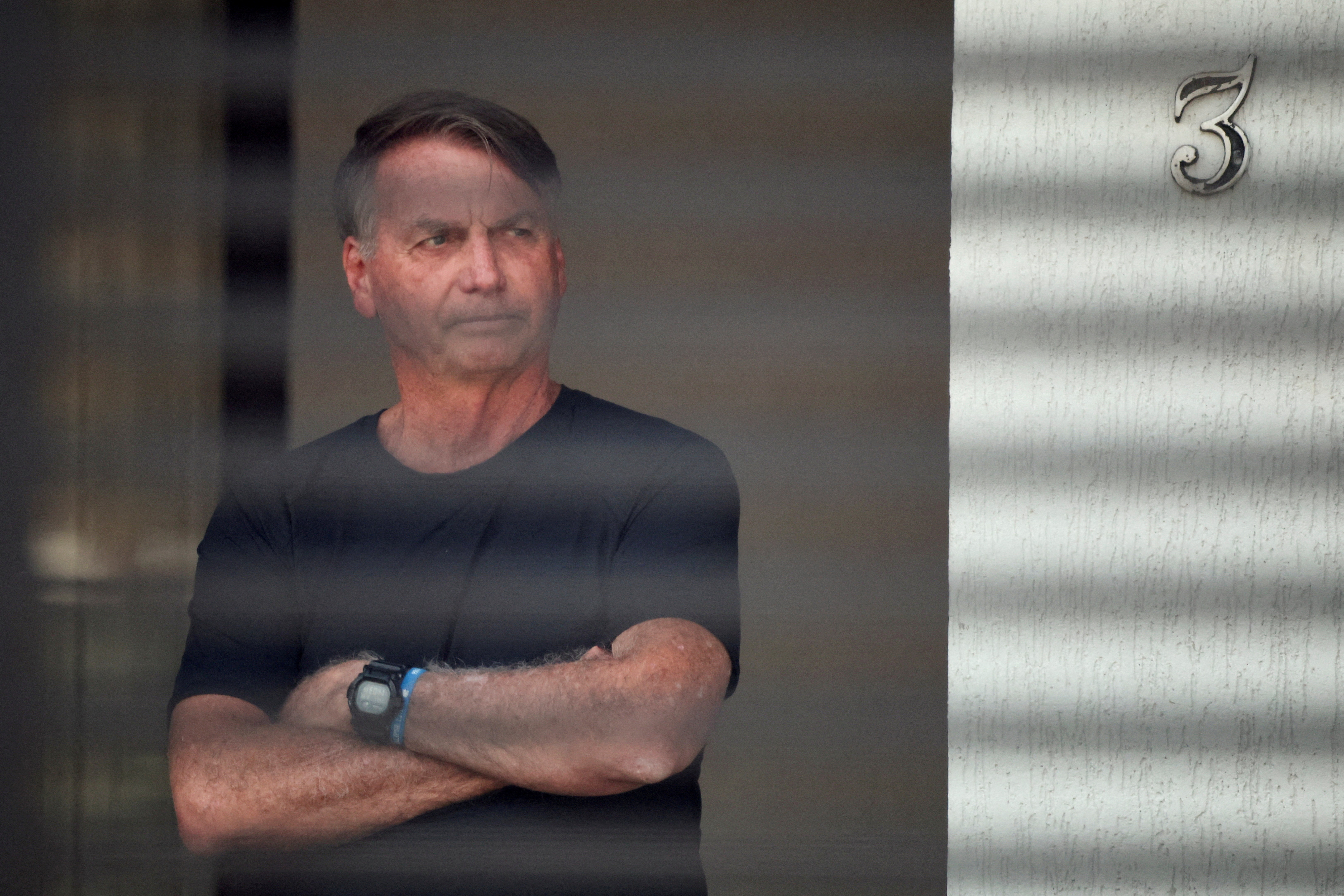 FILE PHOTO: Brazil’s former President Jair Bolsonaro stands at his home while under house arrest, in Brasilia