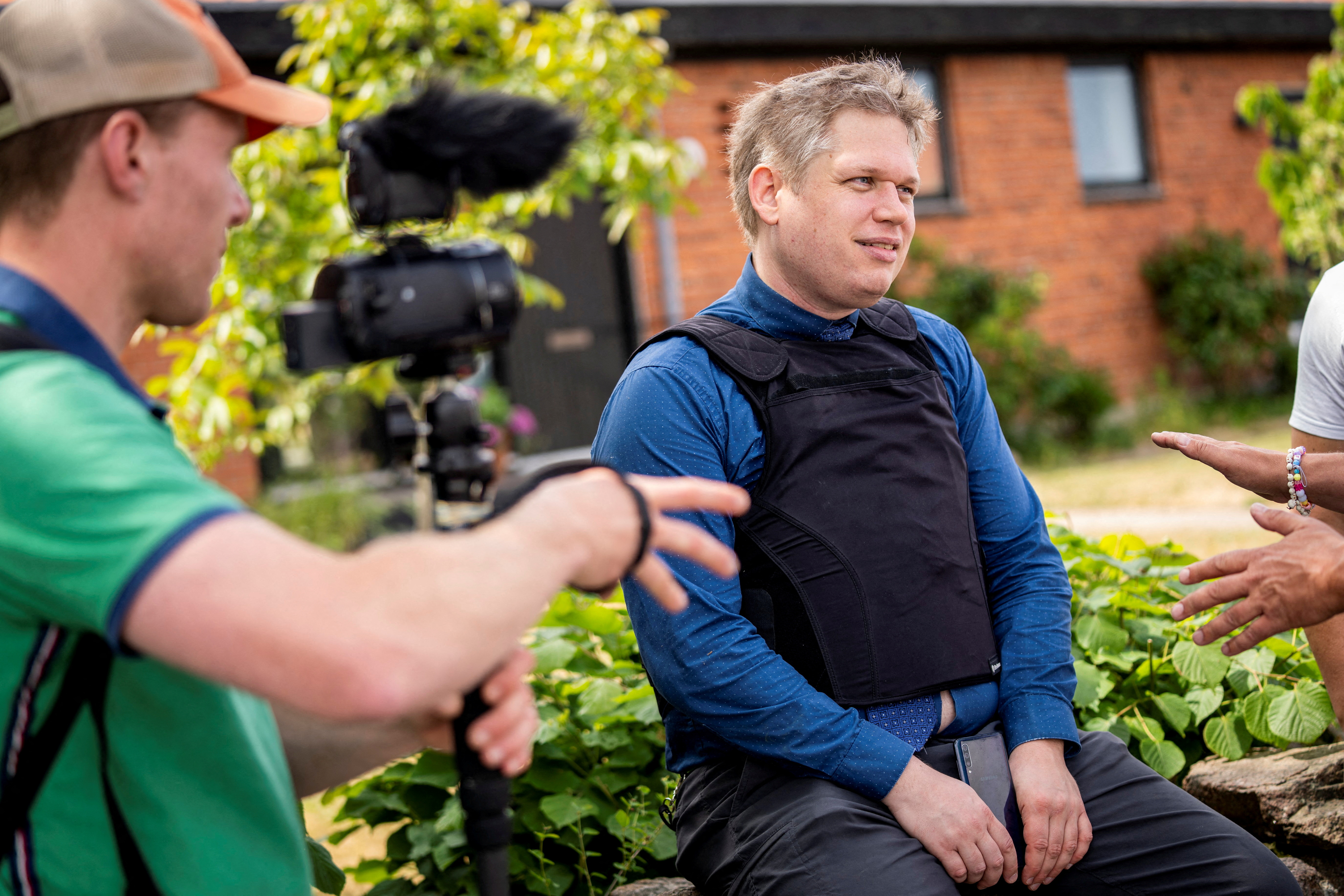 FILE PHOTO: Far-right politician Rasmus Paludan sits outside the prohibition zone as he is being ordered by the police to not participate in the Folkemodet festival in Allinge