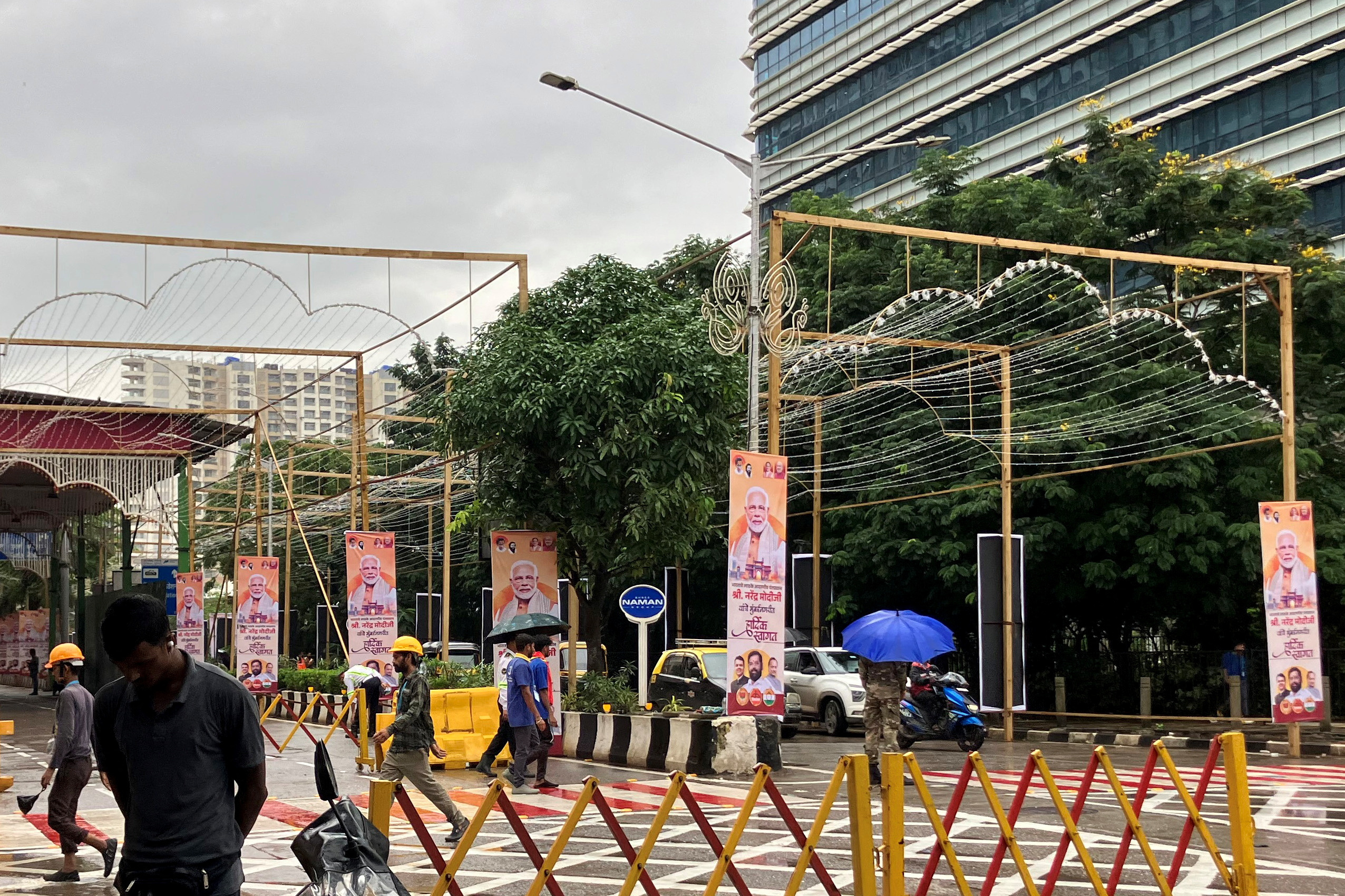 People walk past posters of PM Modi outside Jio World Convention Centre, the wedding venue of Anant Ambani, in Mumbai