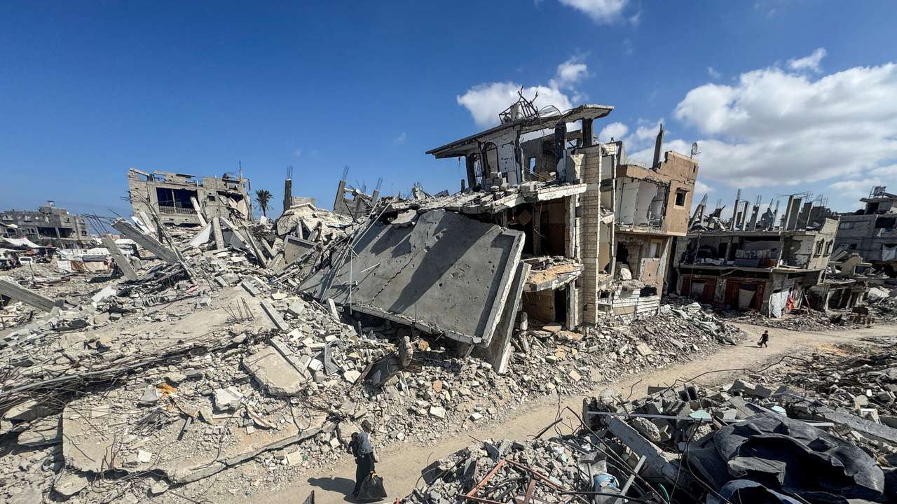 Palestinians walk near rubble and destroyed buildings, in Khan Younis