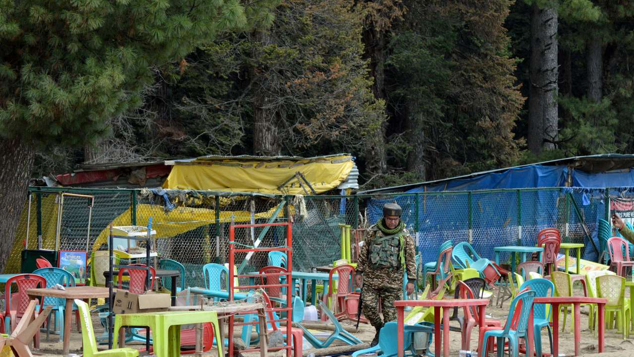 An Indian security force personnel walks amid toppled chairs and tables at the site of a suspected militant attack on tourists in Baisaran