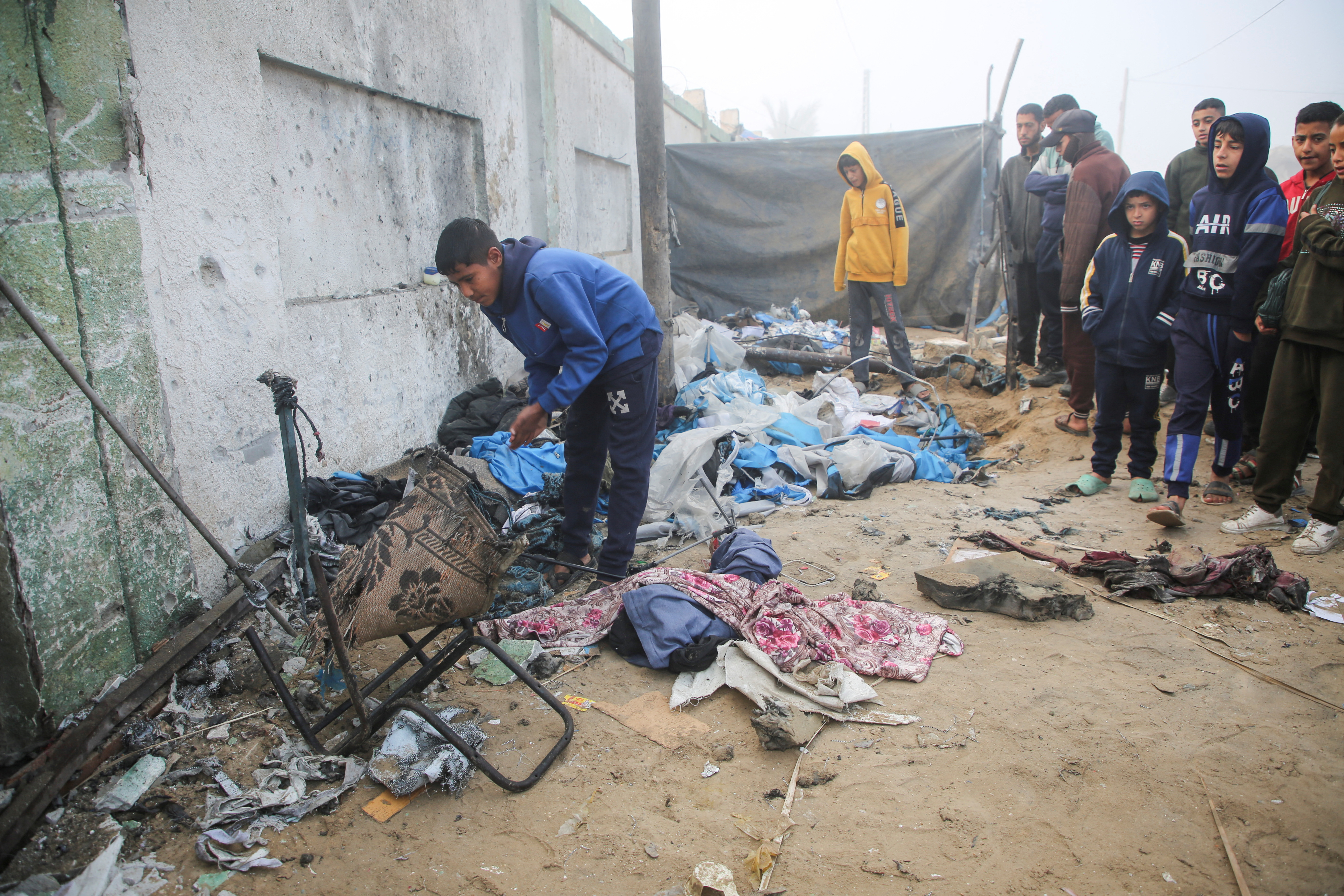 Palestinian boys inspect the damage to a tent for displaced people, after an Israeli airstrike, in Khan Younis
