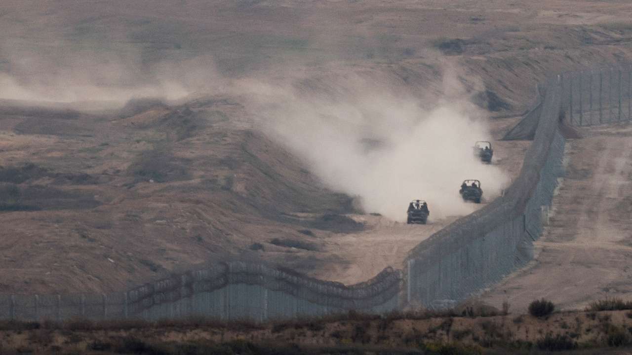 FILE PHOTO: Military vehicles manoeuvre next to a fence, as seen from the Israeli side of the border with Gaza