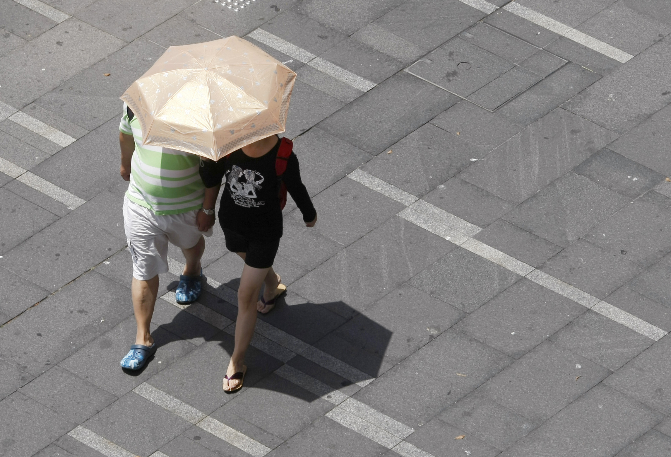 Couple shades themselves from the sun under an umbrella on a hot day in Sydney