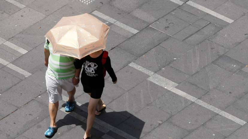 Couple shades themselves from the sun under an umbrella on a hot day in Sydney