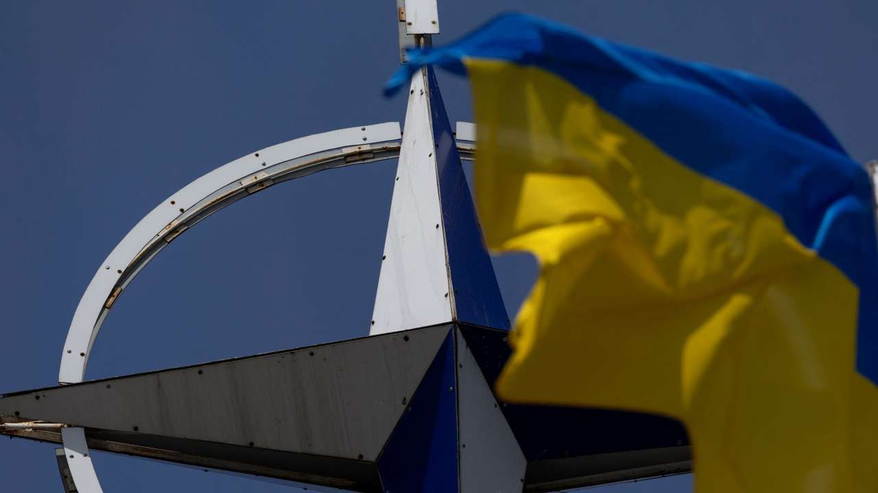 Ukrainian national flag rises in front of the NATO emblem in central Kyiv