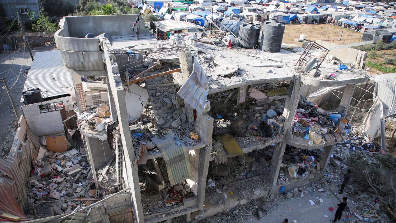 People stand next to a house damaged in an Israeli strike, amid the ongoing conflict between Israel and the Palestinian Islamist group Hamas, in Rafah