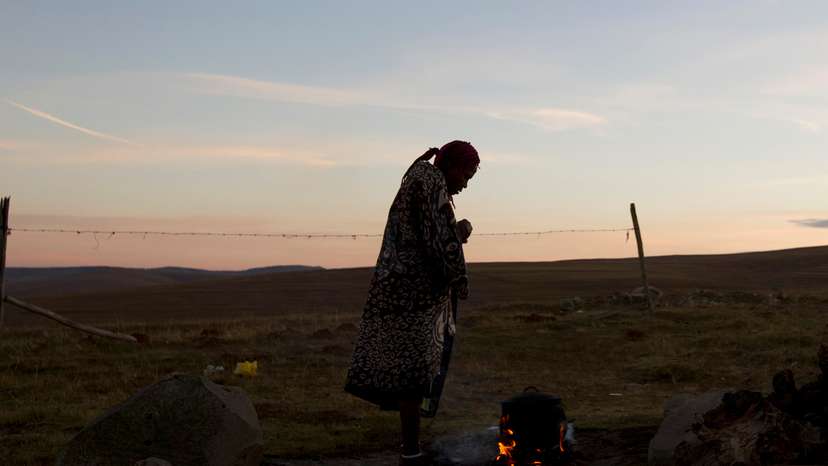 A woman warms water on an open fire near the home of former South African President Nelson Mandela's house in Qunu