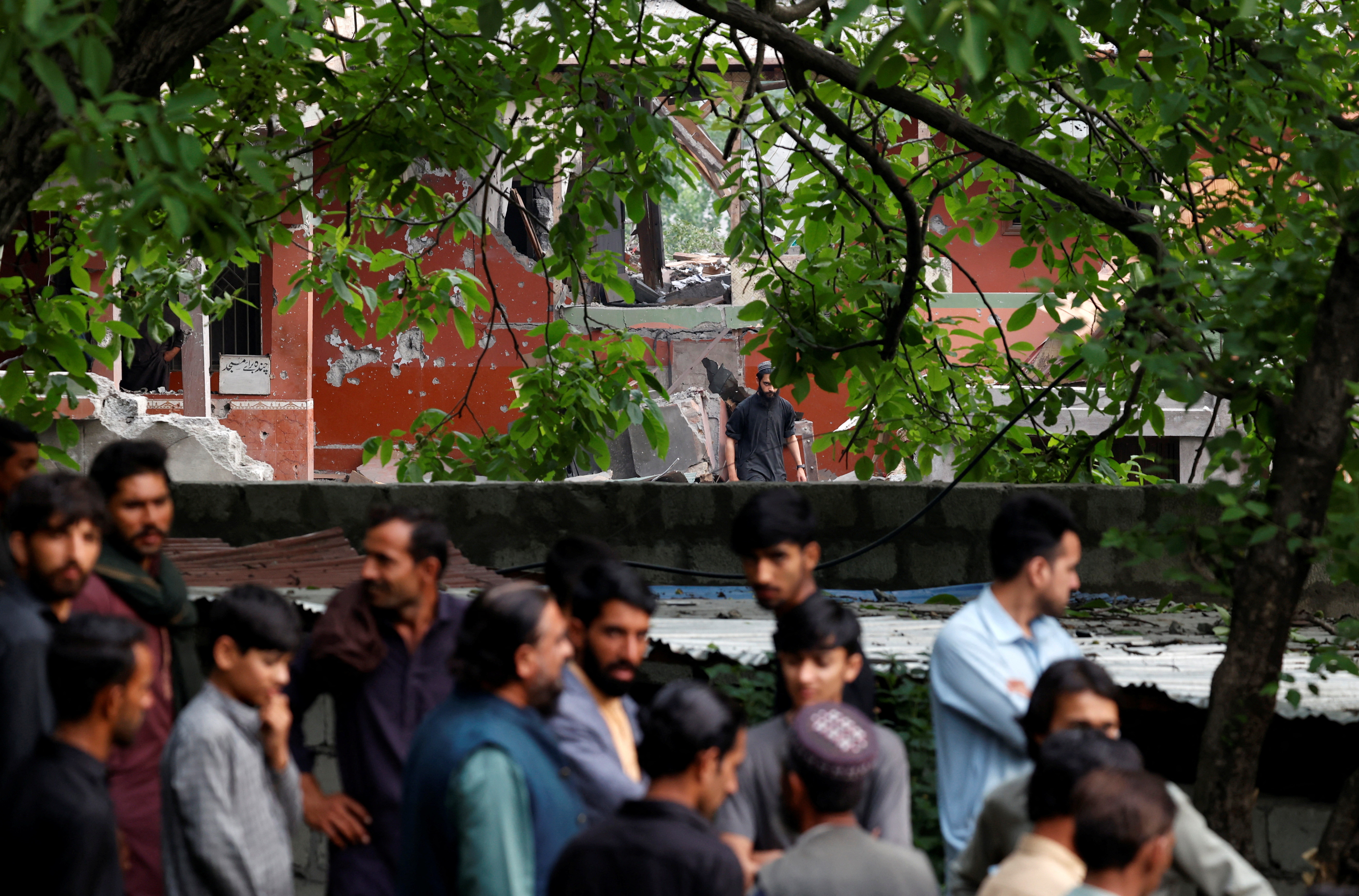 People gather next to a damaged portion of Bilal Mosque after it was hit by an Indian strike in Muzaffarabad