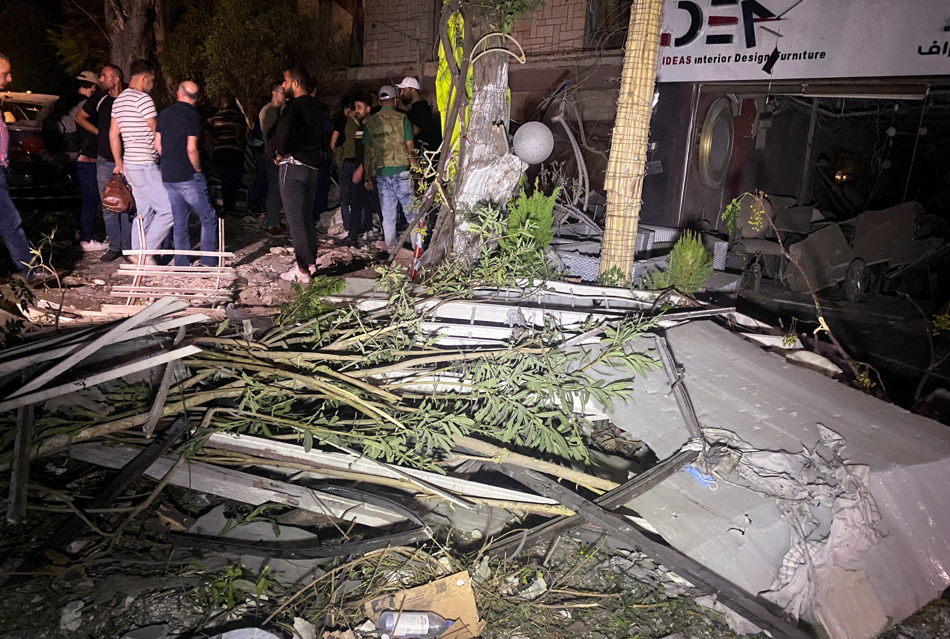 People gather near the site of an Israeli airstrike, in Damascus