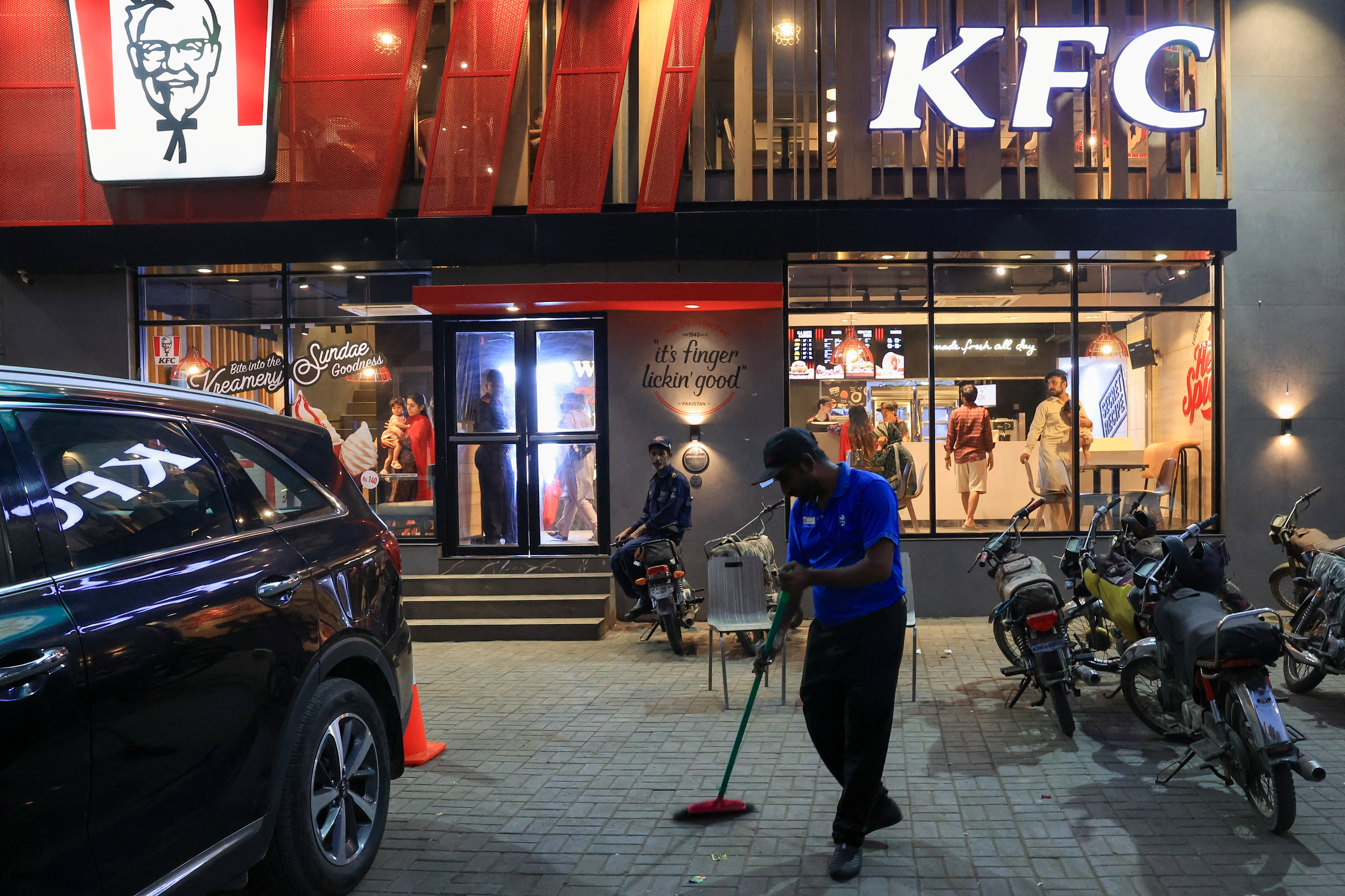 A worker clears the floor at the Kentucky Fried Chicken (KFC) fast food outlet, in Karachi