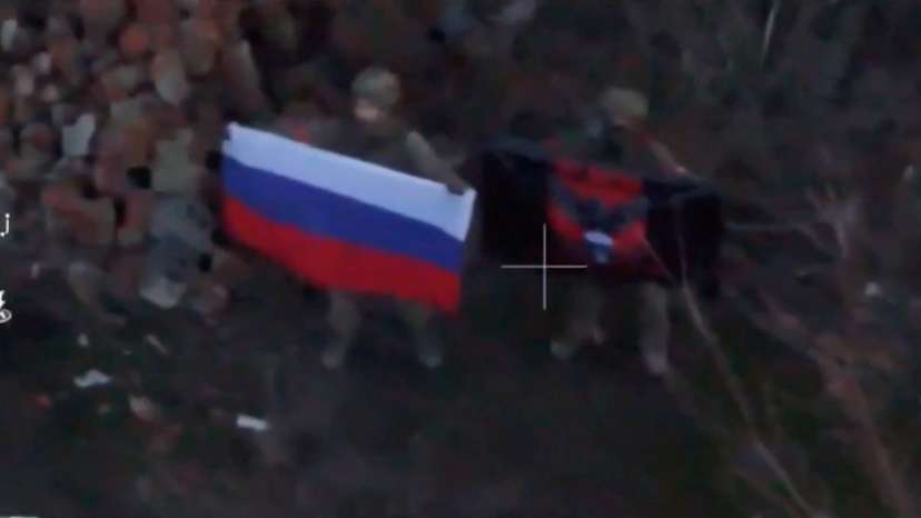 A soldier holds up a Russian flag in Kurakhove, Donetsk Region