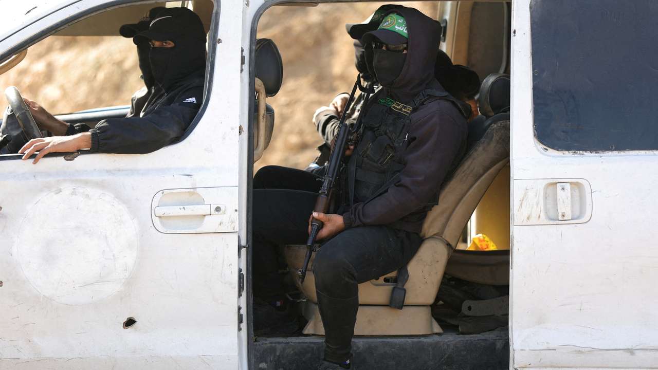Hamas militants escort members of the Red Cross towards an area within the so-called "yellow line", in Gaza City