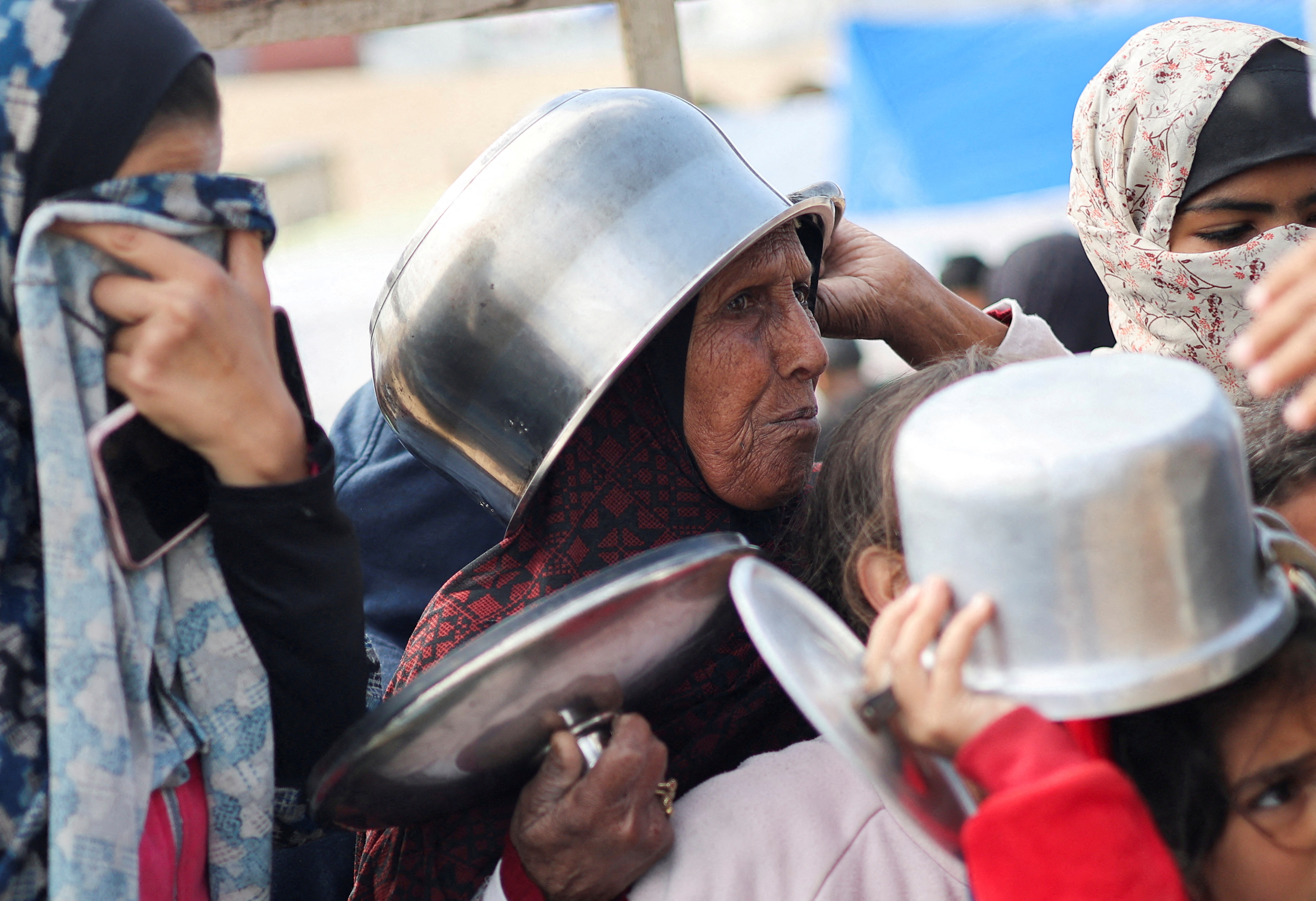 Displaced Palestinians wait to receive free food at a tent camp, amid food shortages, in Rafah