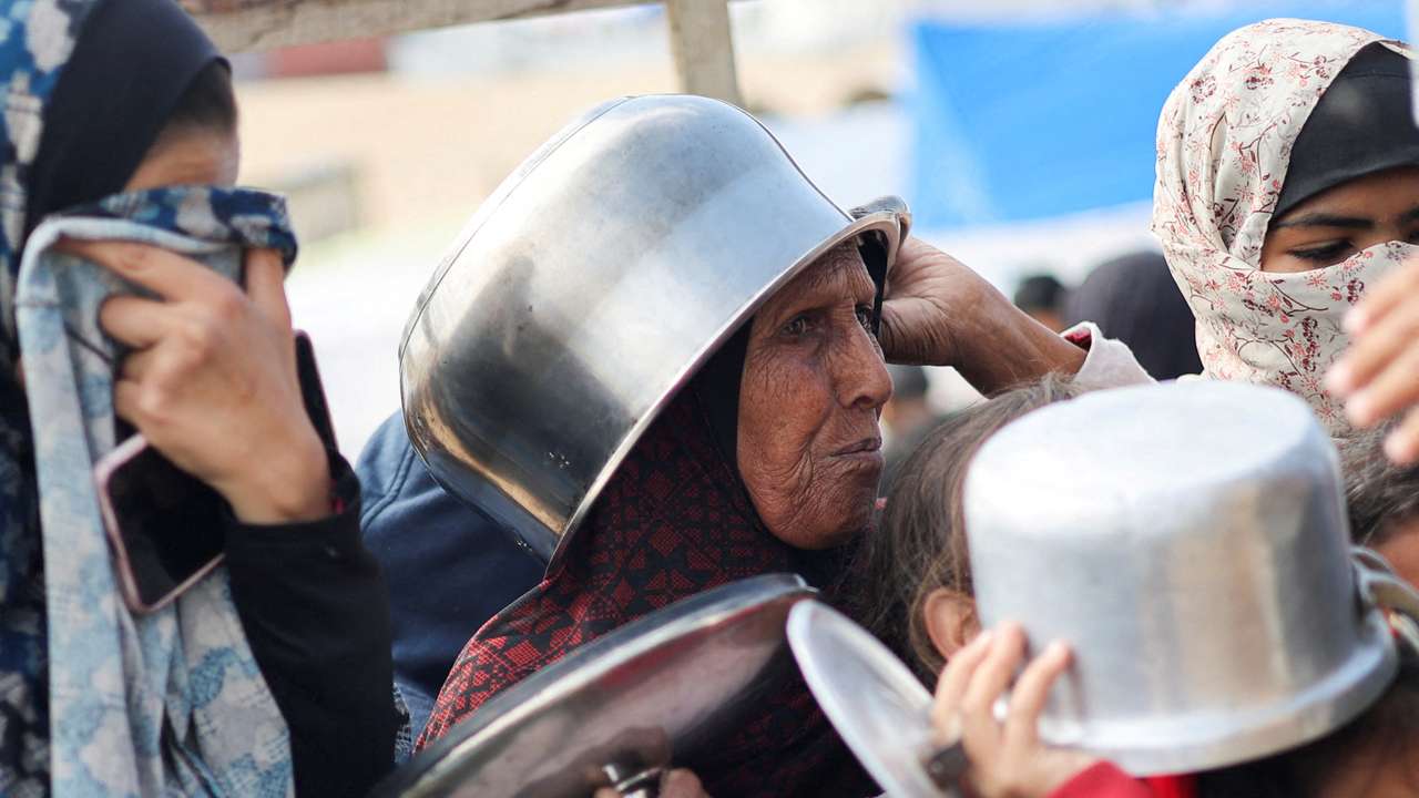 Displaced Palestinians wait to receive free food at a tent camp, amid food shortages, in Rafah