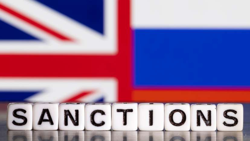 Illustration shows letters arranged to read "Sanctions" in front of Union Jack and Russian flag colors