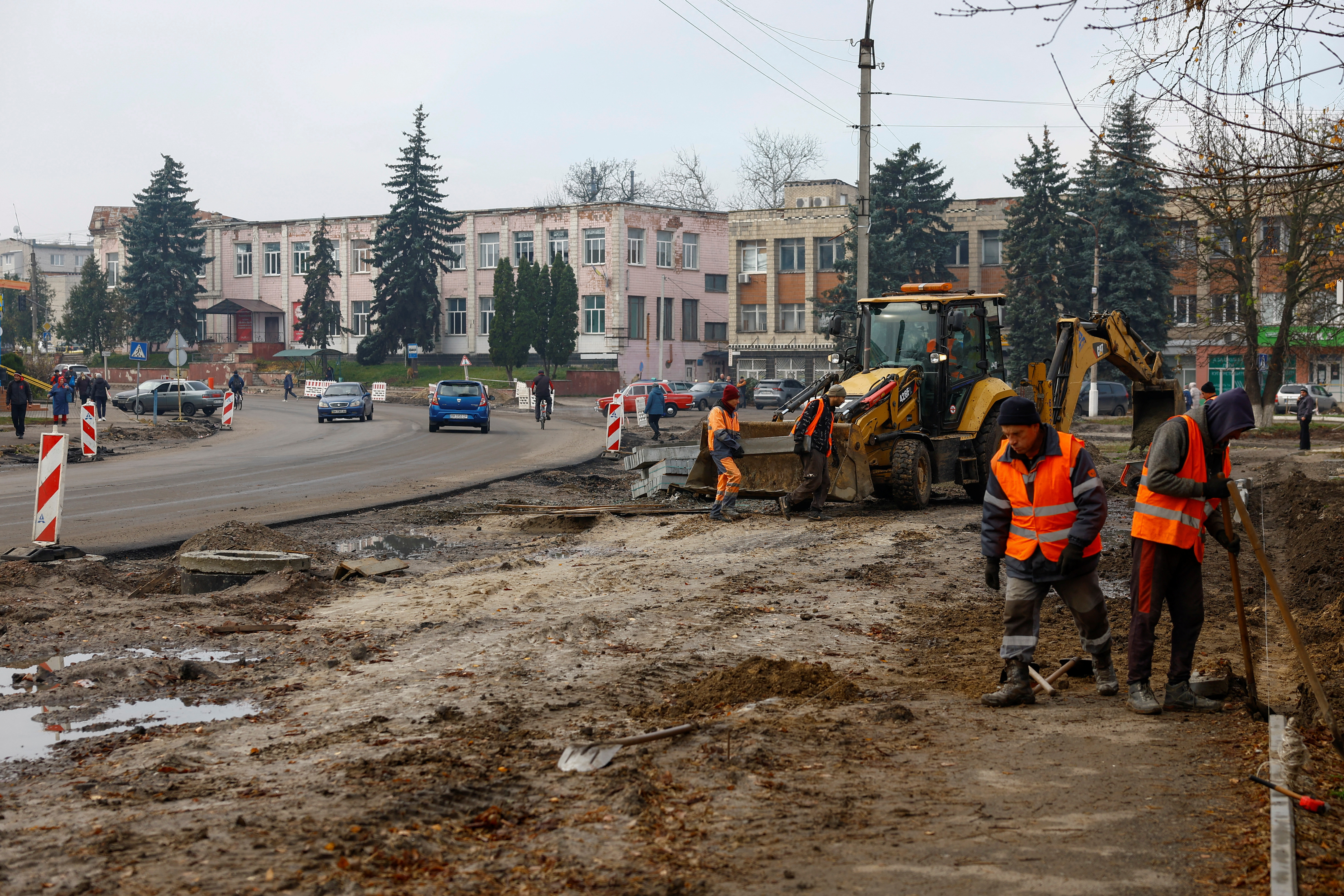 Workers reconstruct a street, which was damaged on the first months of Russia's attack on Ukraine in the town of Trostianets