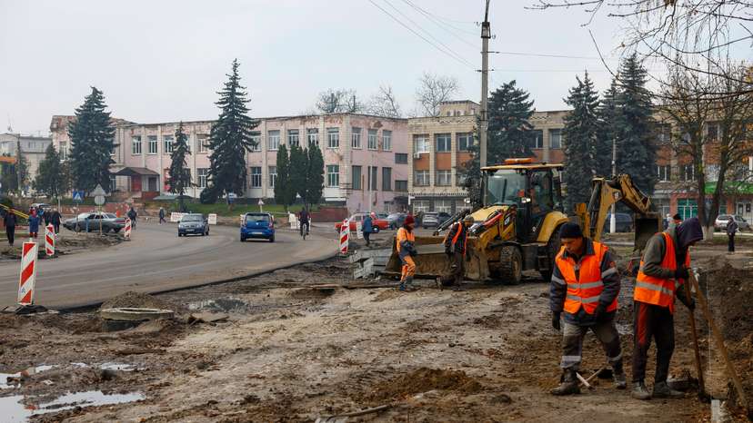 Workers reconstruct a street, which was damaged on the first months of Russia's attack on Ukraine in the town of Trostianets