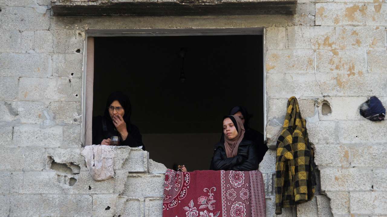 Palestinian women stand in a window of a damaged building, amid ceasefire negotiations with Israel, in Gaza City