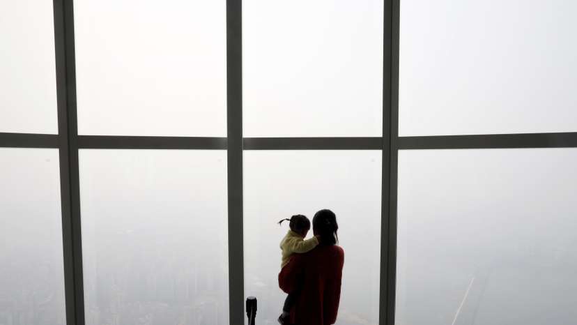 A woman holding her baby in her arms looks at a view of Seoul shrouded by fine dust during a polluted day in Seoul