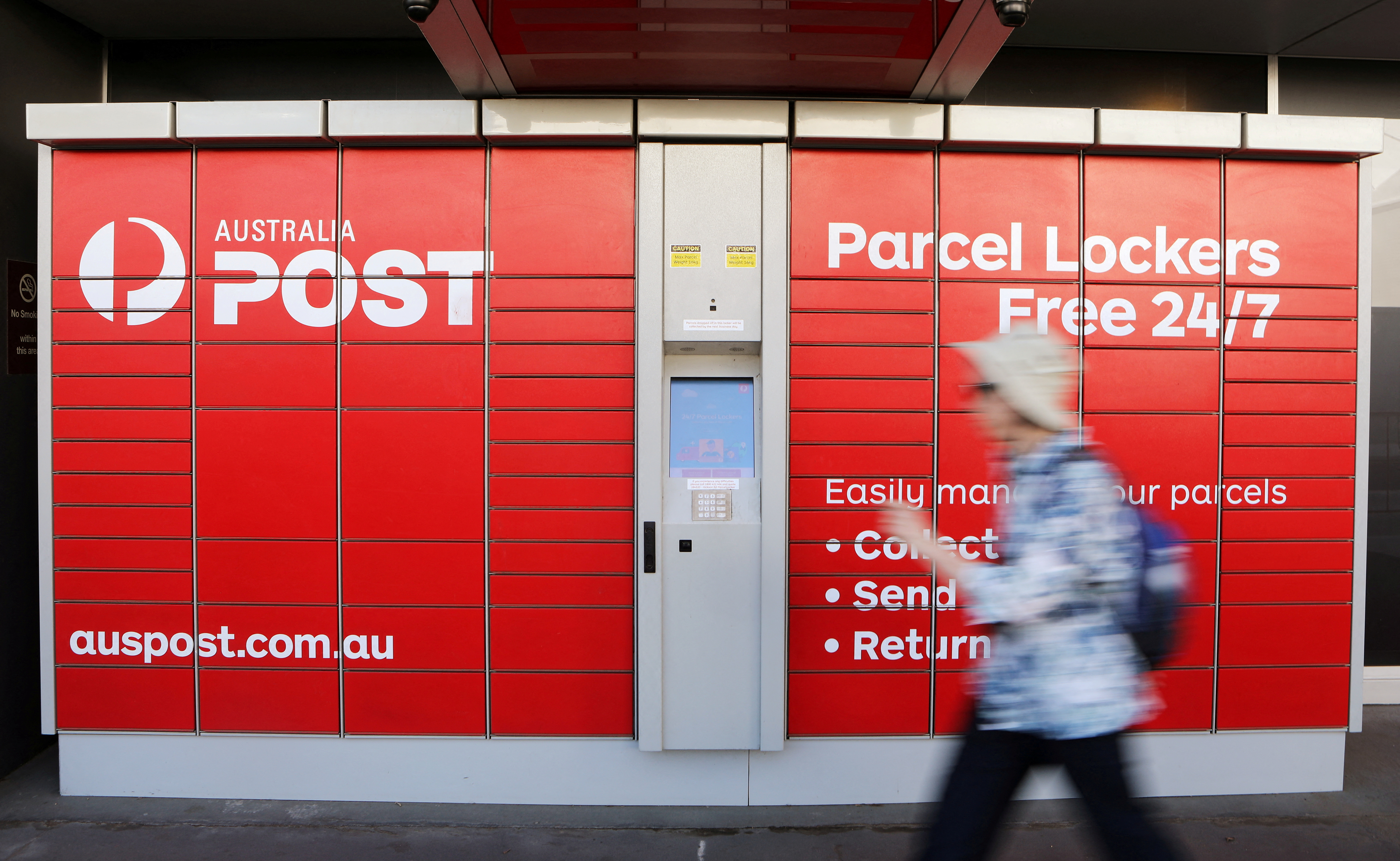 FILE PHOTO: A woman walks past Australia Post parcel lockers in Sydney