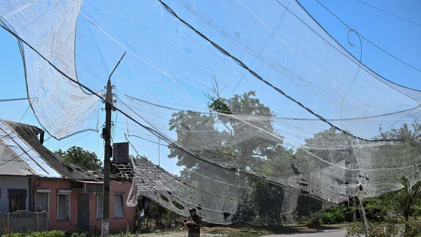 Ukrainian service member walks on a street protected with anti-drone nets in the frontline town Orikhiv