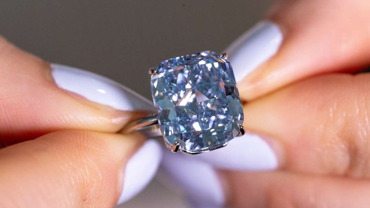 A Sotheby’s staff holds "The Mediterranean Blue" diamond during an auction preview in Geneva