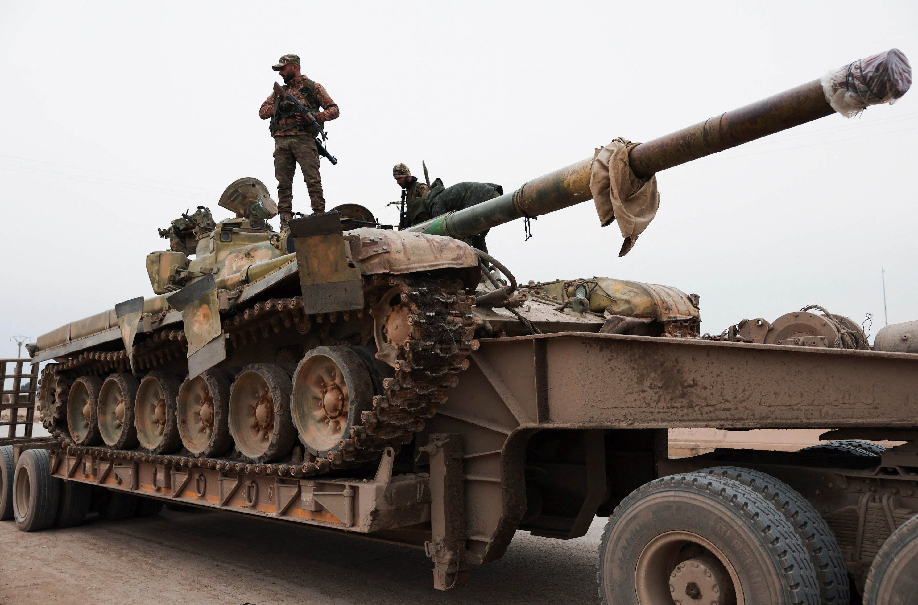A member of the Syrian army stands over a tank, in Maskanah