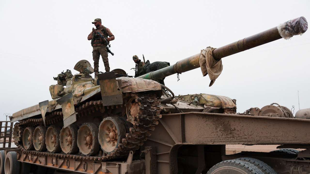 A member of the Syrian army stands over a tank, in Maskanah