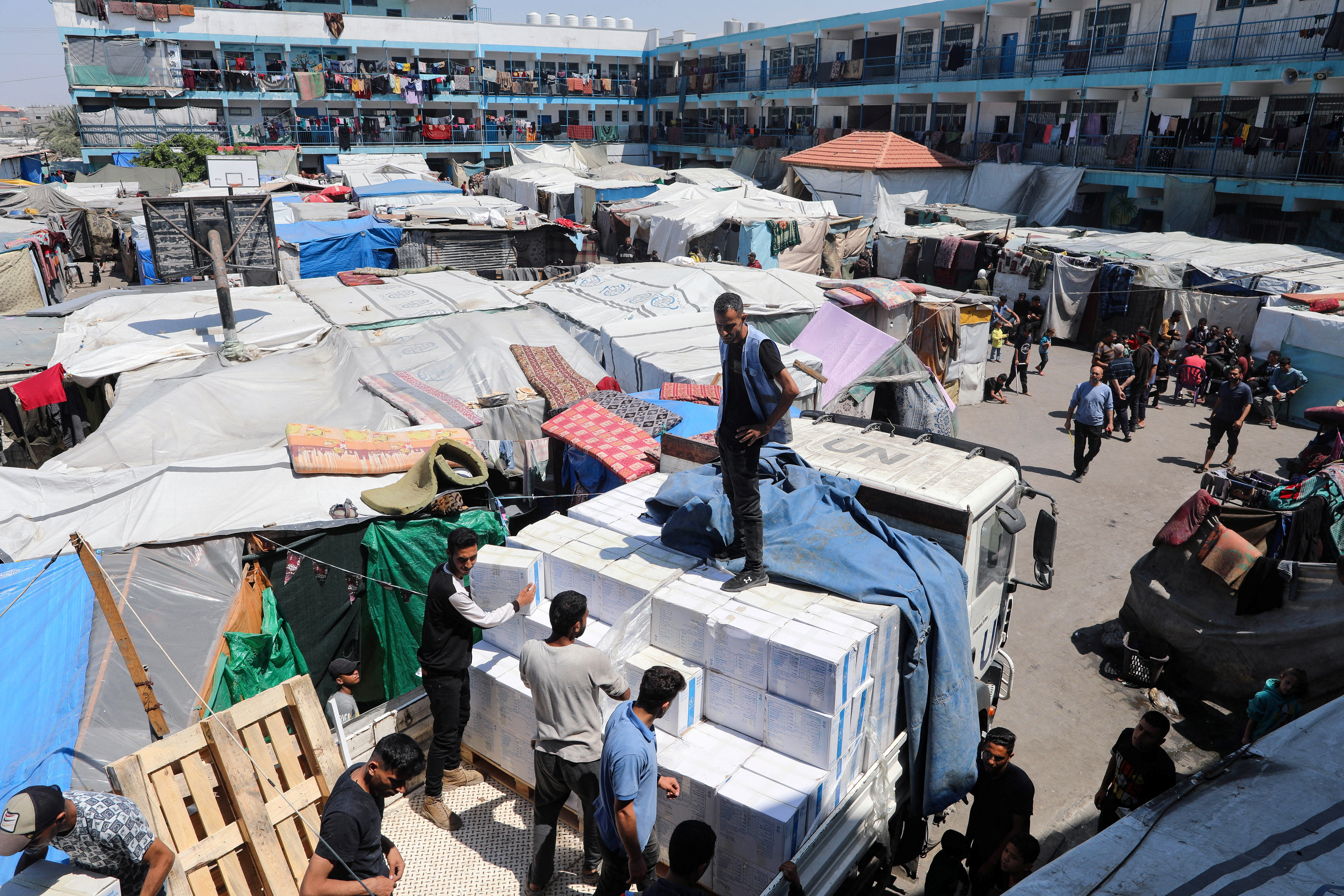 FILE PHOTO: Palestinians distribute aid at a shelter center in Deir Al-Balah