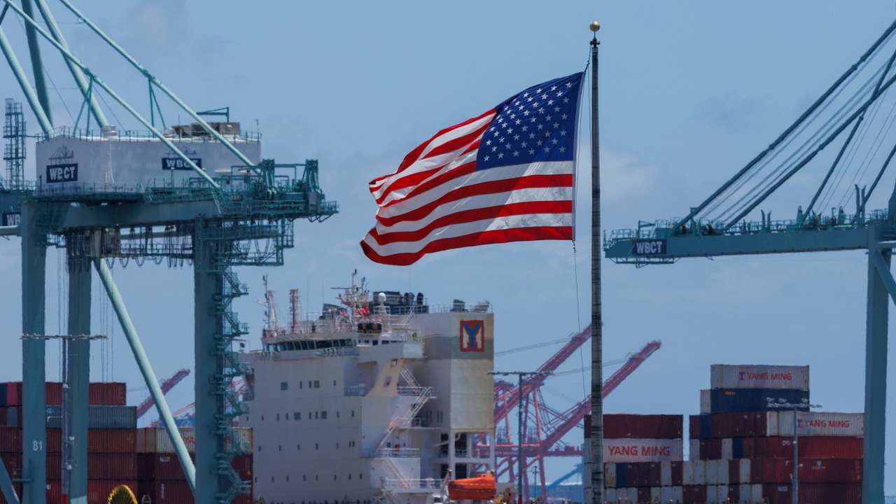The American flag flutters near a ship at Port of Los Angeles