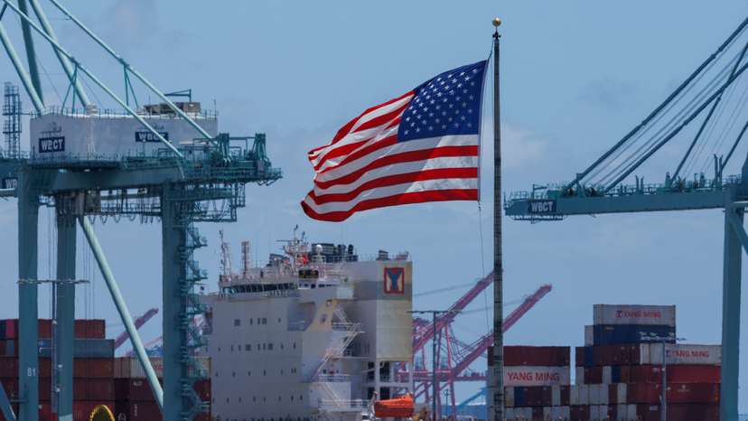 The American flag flutters near a ship at Port of Los Angeles