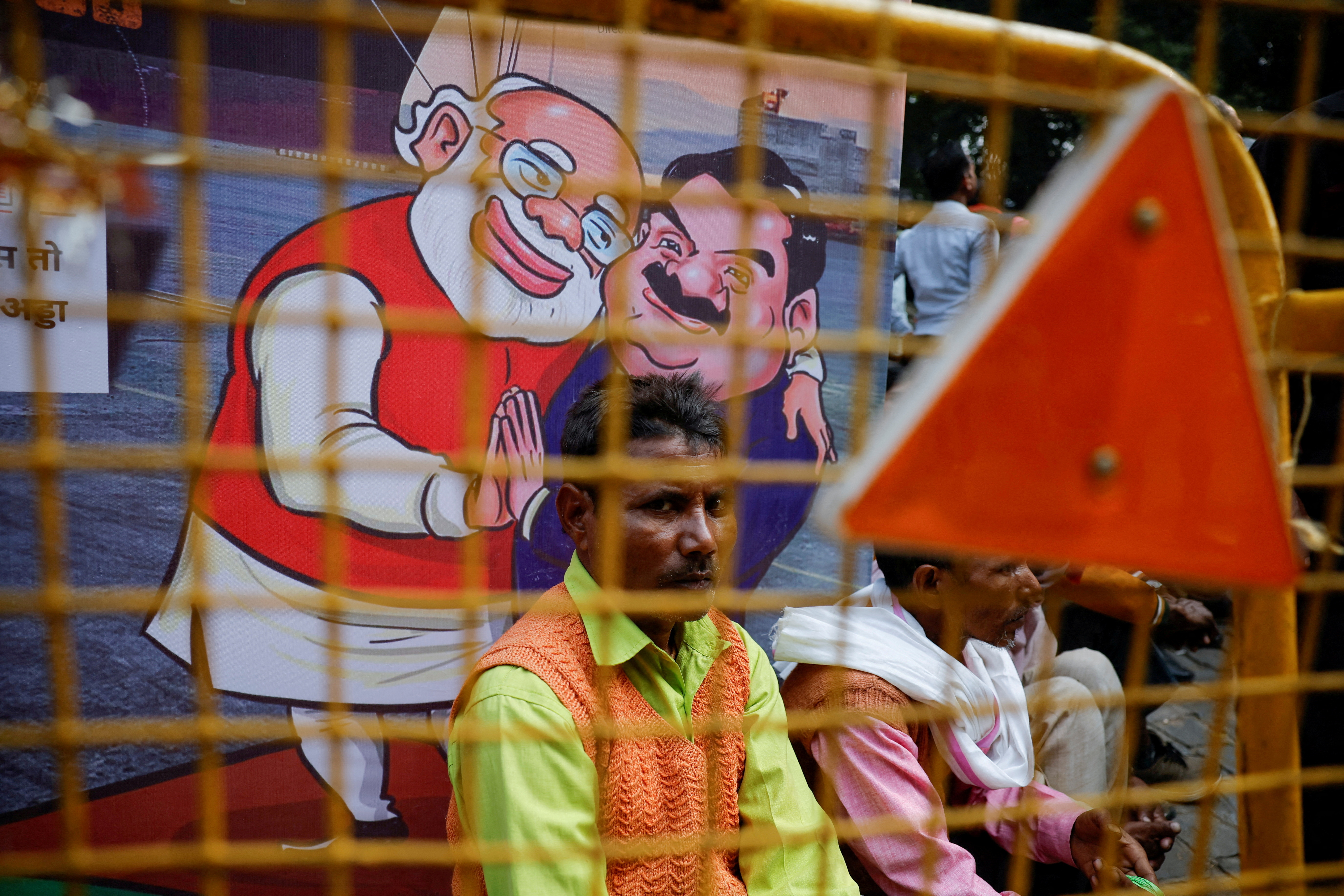 FILE PHOTO: A man sits next to a poster put up during a protest by India's main opposition Congress party against Indian billionaire Gautam Adani, in New Delhi