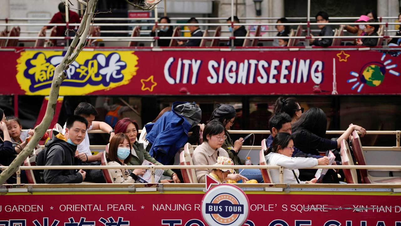 Tourists ride on a tourist double-decker bus in Shanghai