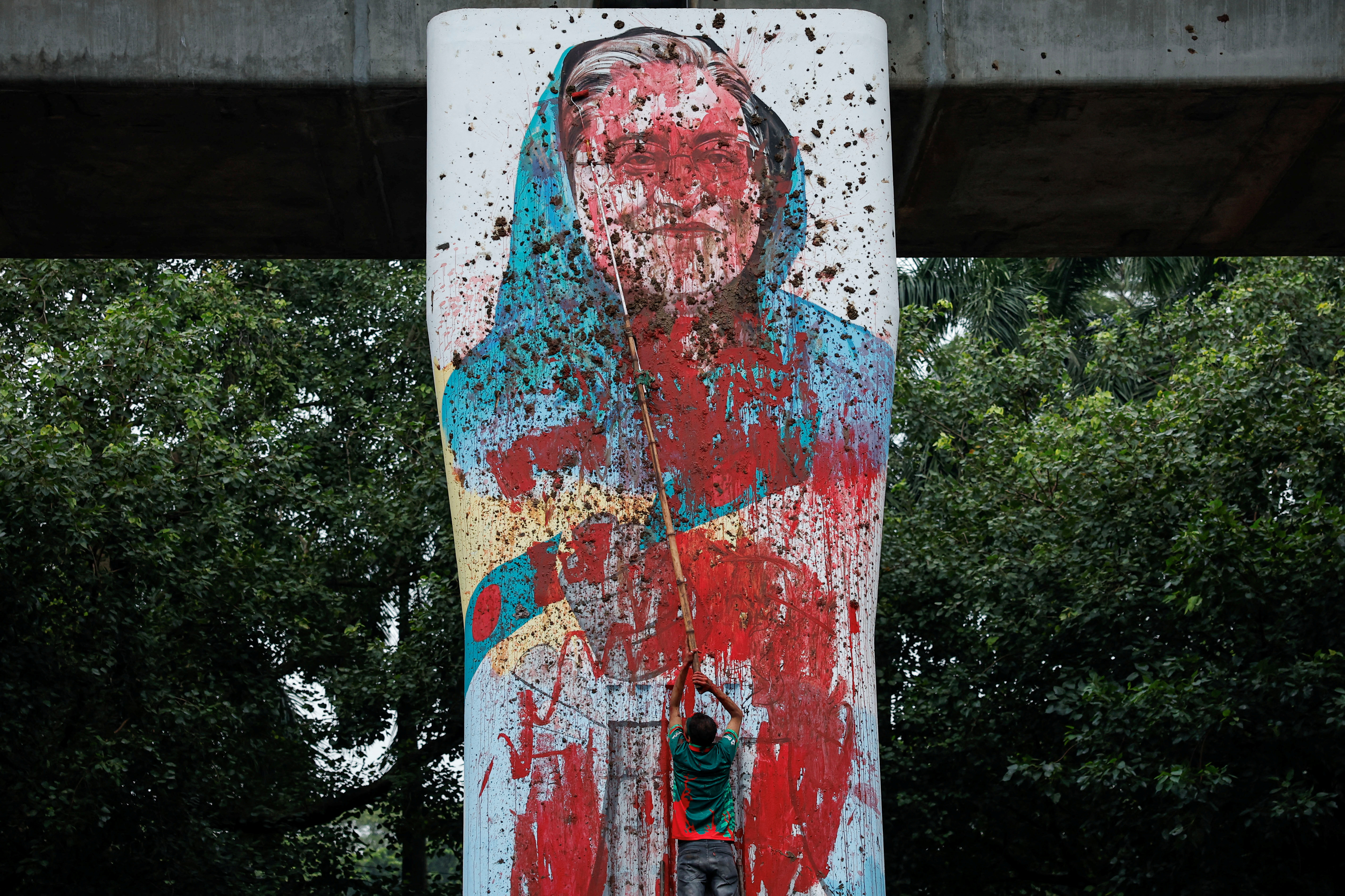 A protester vandalises a mural of Bangladeshi PM Hasina with paint, demanding her resignation at University of Dhaka