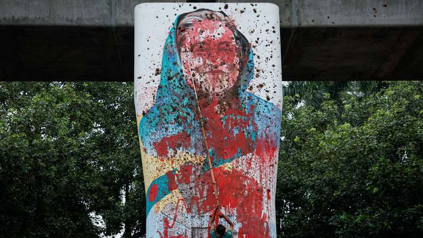 A protester vandalises a mural of Bangladeshi PM Hasina with paint, demanding her resignation at University of Dhaka