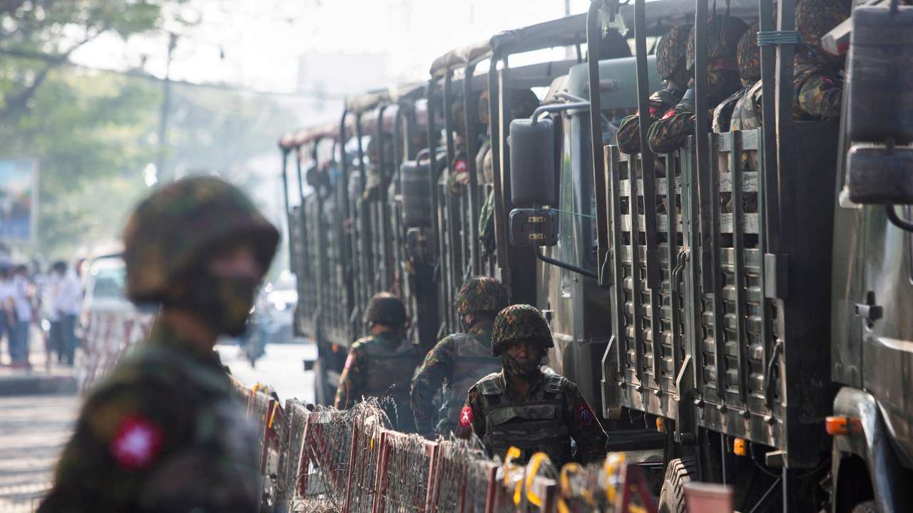 FILE PHOTO: Soldiers stand next to military vehicles as people gather to protest against the military coup, in Yangon