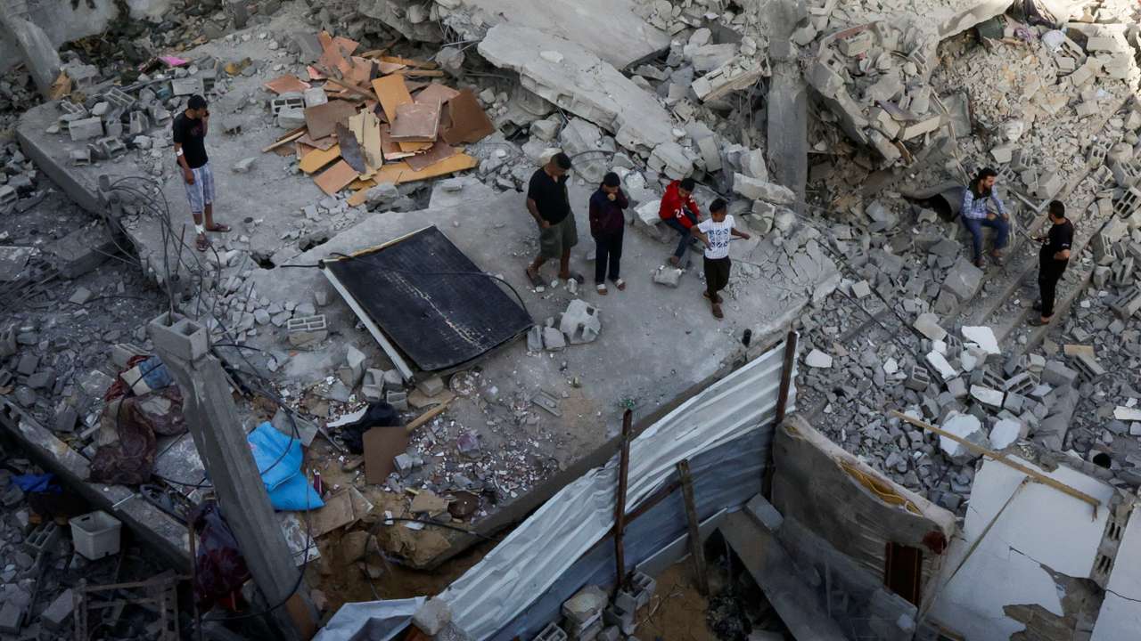 Palestinians inspect the site of an Israeli strike on a house, in Khan Younis