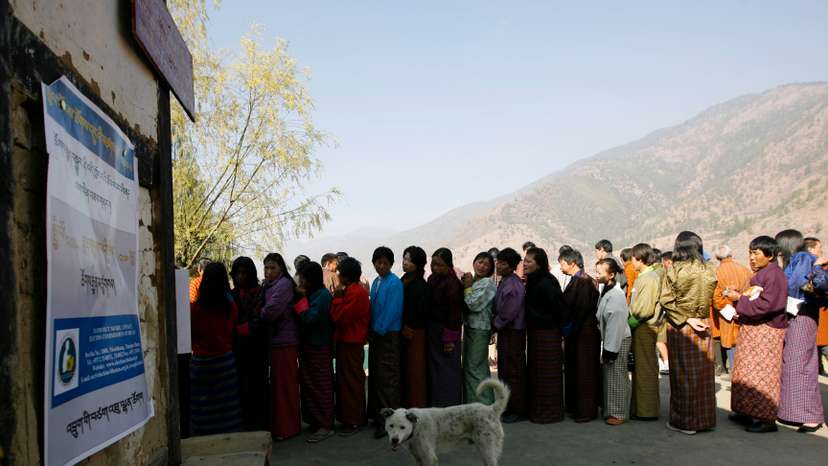 FILE PHOTO: Bhutanese voters stand in a queue outside a polling station to cast their ballot in Thimpu