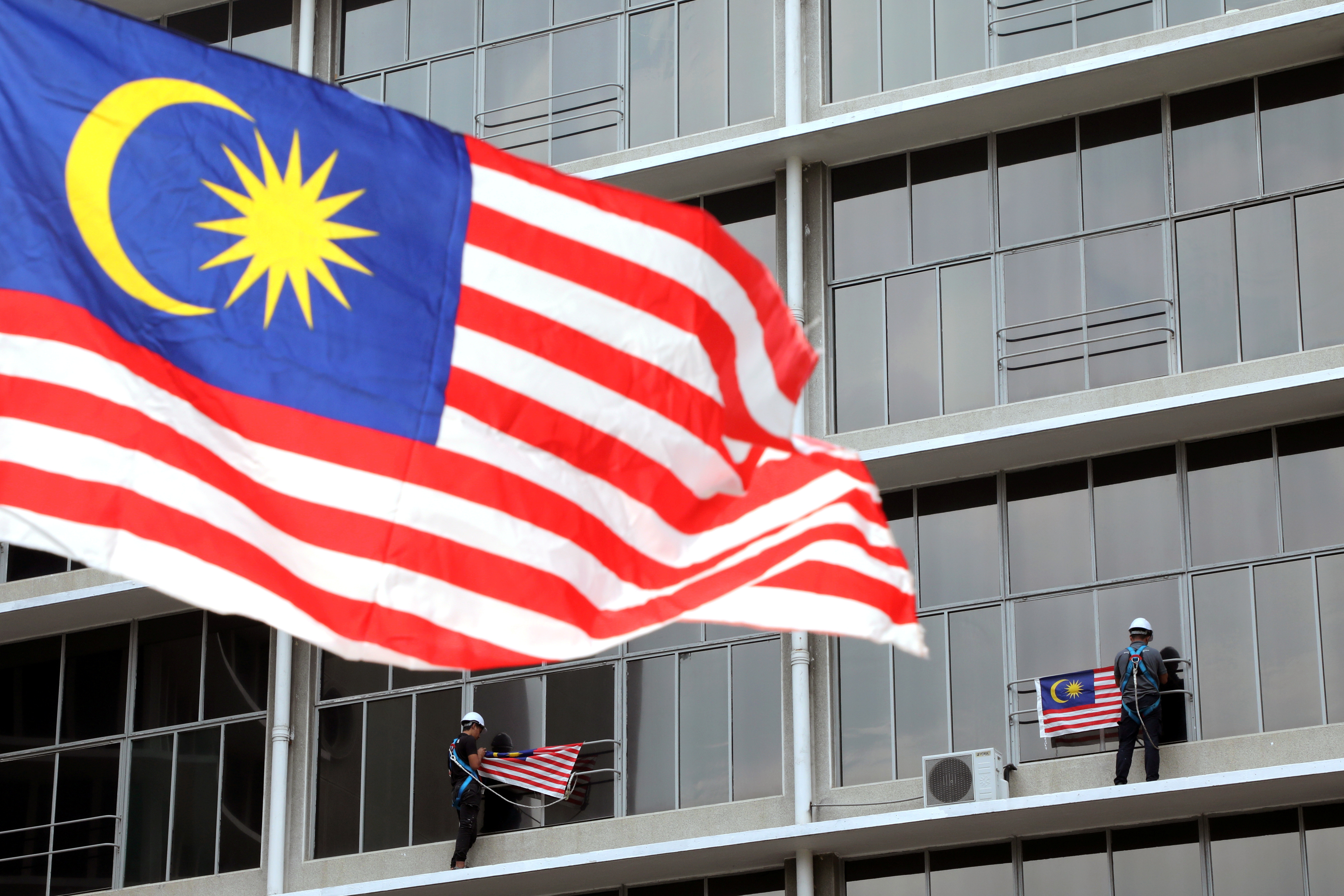 Workers hang Malaysian flags ahead of celebrations for the country’s 62nd anniversary of independence on August 31 in Kuala Lumpur