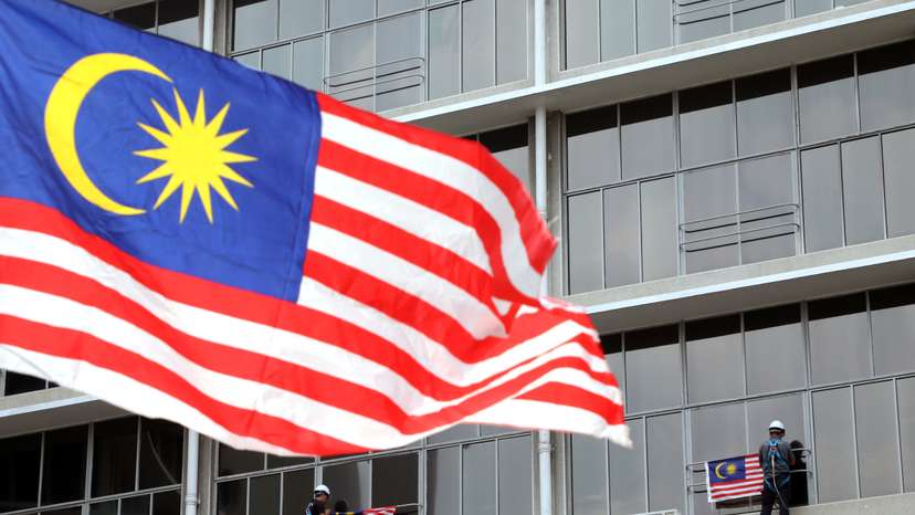 Workers hang Malaysian flags ahead of celebrations for the country’s 62nd anniversary of independence on August 31 in Kuala Lumpur
