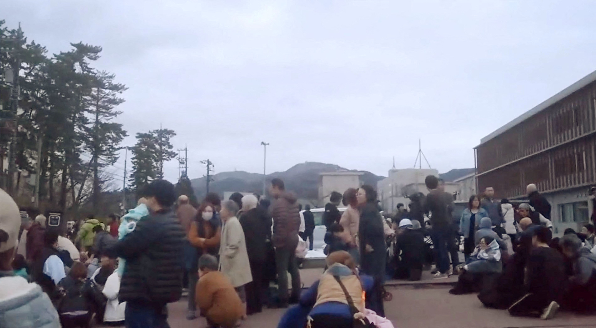 People evacuate to higher ground at a parking space of a junior high school after a tsunami warning issued caused by an earthquake in Wajima