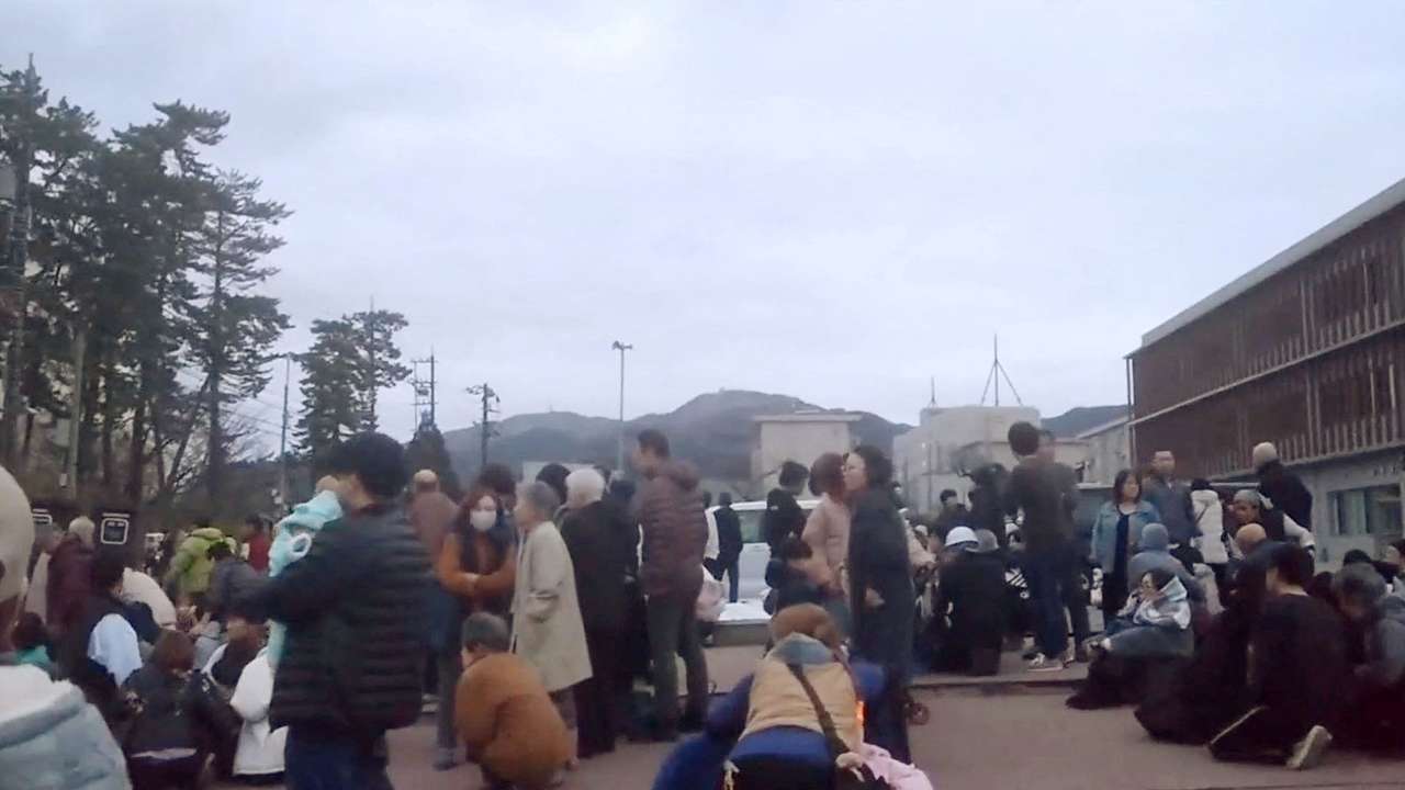 People evacuate to higher ground at a parking space of a junior high school after a tsunami warning issued caused by an earthquake in Wajima