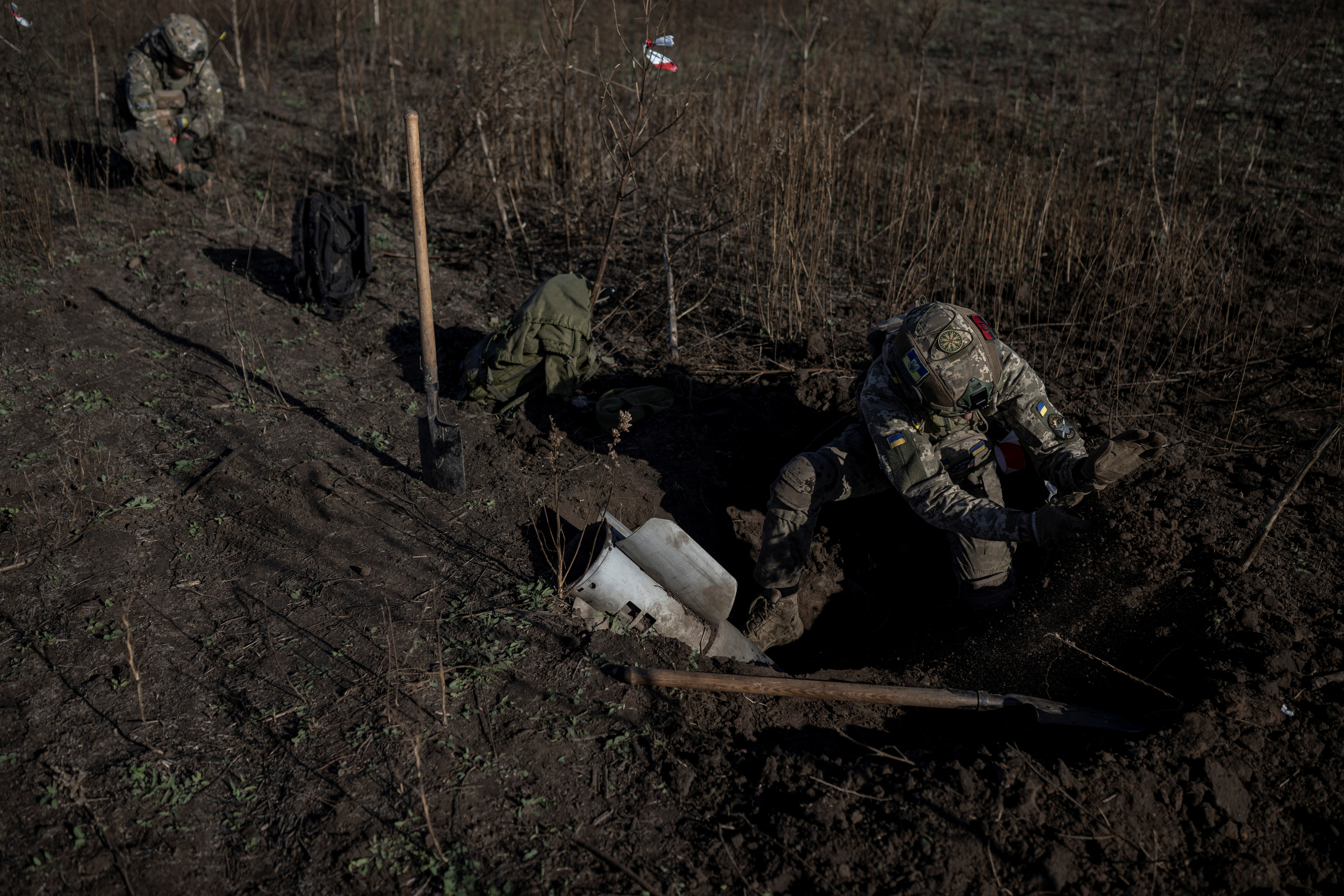Ukrainian sappers dig up a rocket of multiple launch system in a field in Kherson region