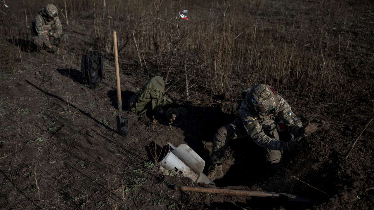 Ukrainian sappers dig up a rocket of multiple launch system in a field in Kherson region