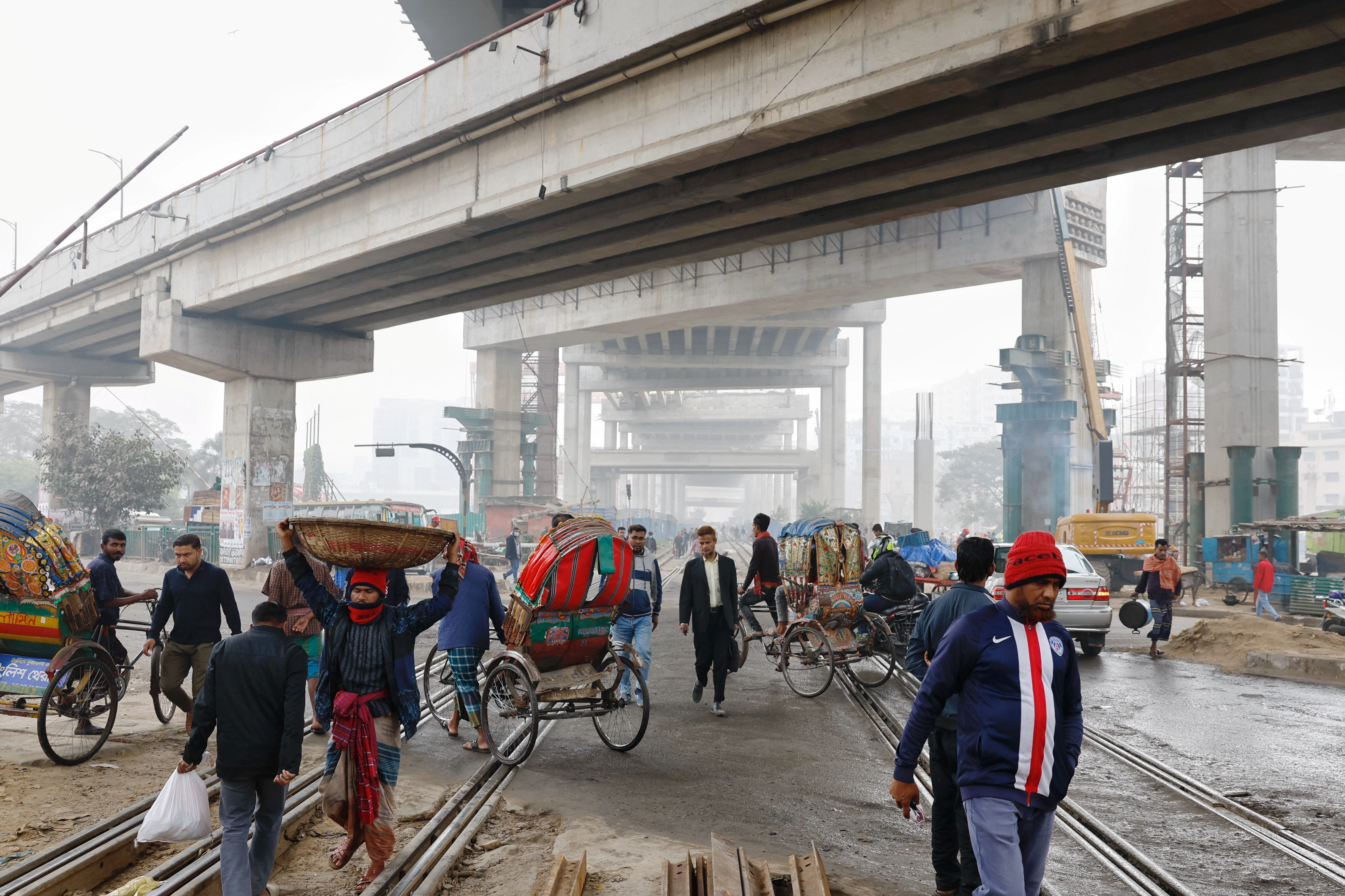 People and vehicles pass through rail tracks at the Karwan Bazar area, in Dhaka