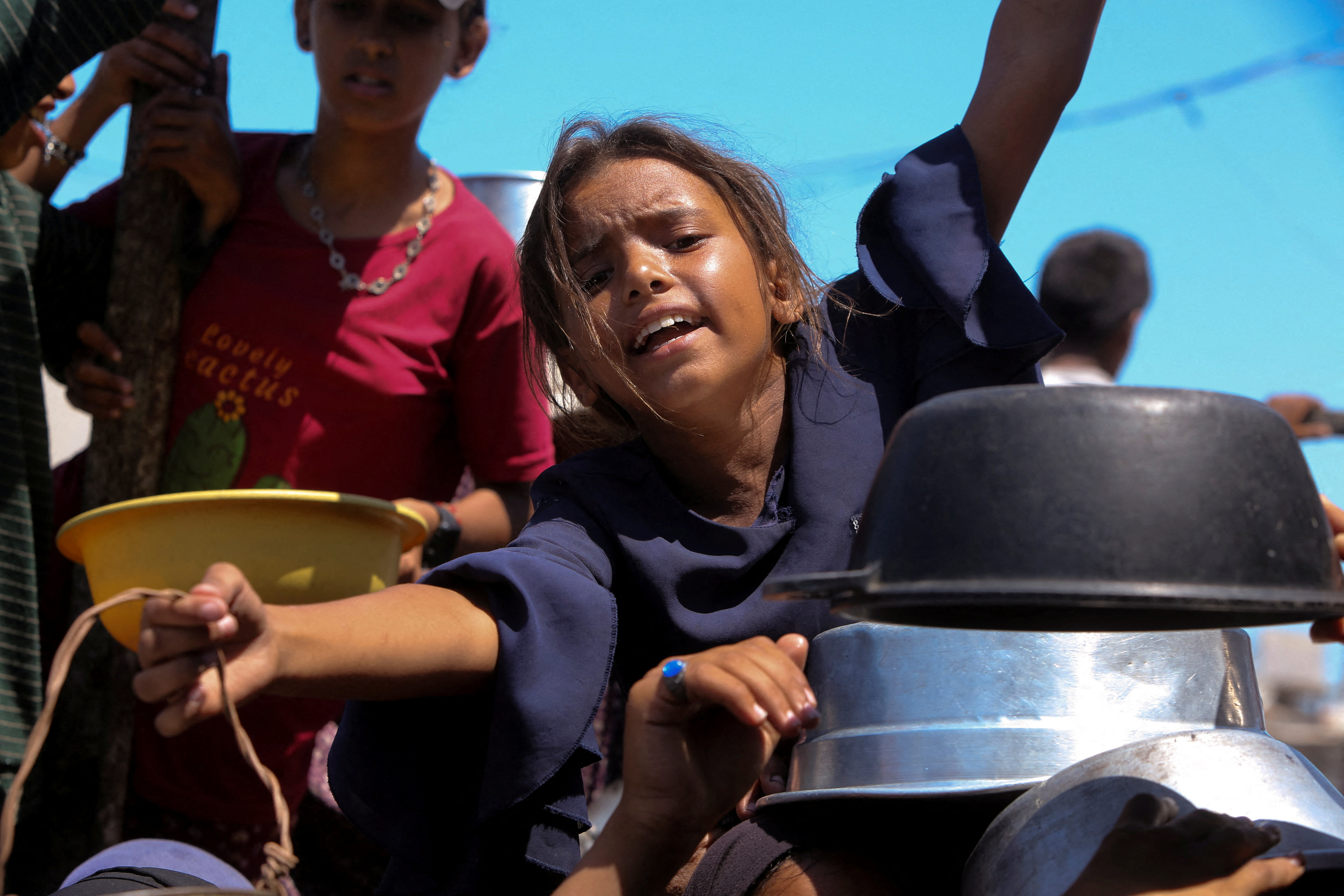 Palestinians wait to receive food from a charity kitchen, amid a hunger crisis, in Khan Younis