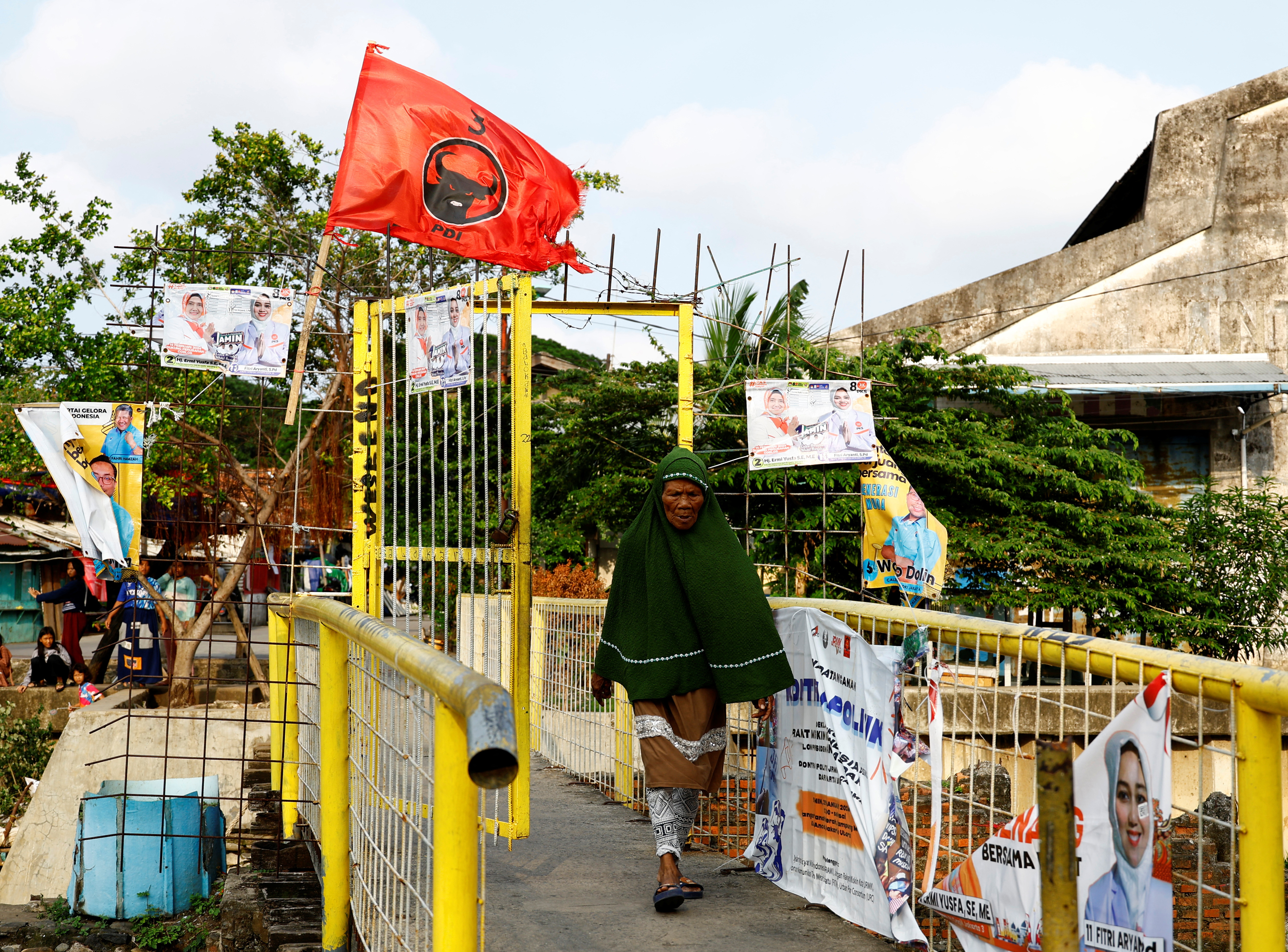FILE PHOTO: A woman walks past a flag of the ruling Indonesian Democratic Party of Struggle (PDI-P) at a residential area in Jakarta