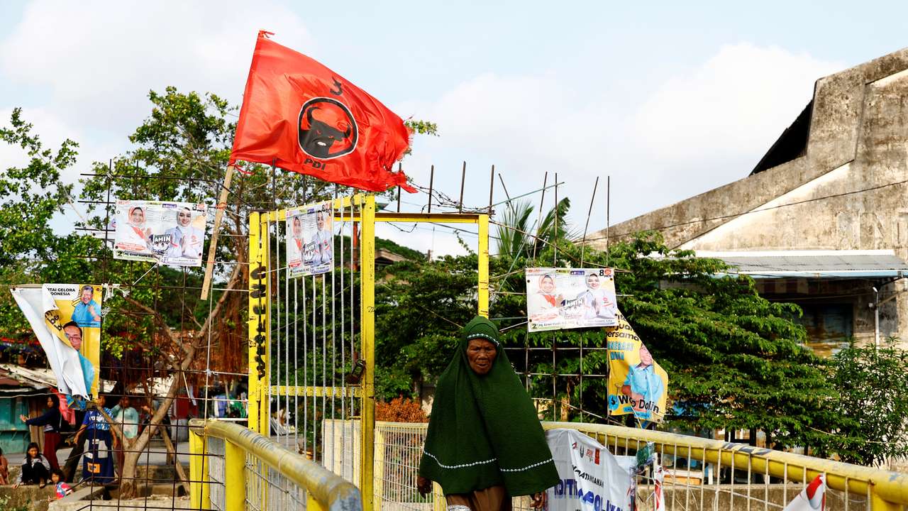 FILE PHOTO: A woman walks past a flag of the ruling Indonesian Democratic Party of Struggle (PDI-P) at a residential area in Jakarta